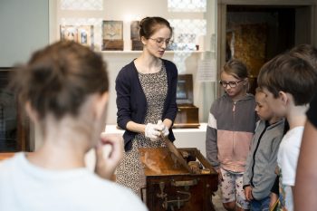 Pracownik Muzeum pokazuje grupie dzieci wnętrze katarynki