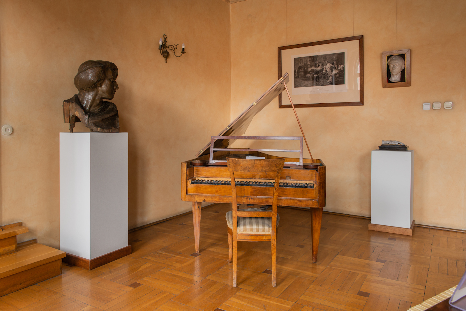 Zabytkowy fortepian w centrum, po jego lewej stronie popiersie Fryderyka Chopina