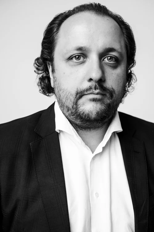 Czarno-białe zdjęcie mężczyzny o dłuższych, zaczesanych do tyłu włosach.