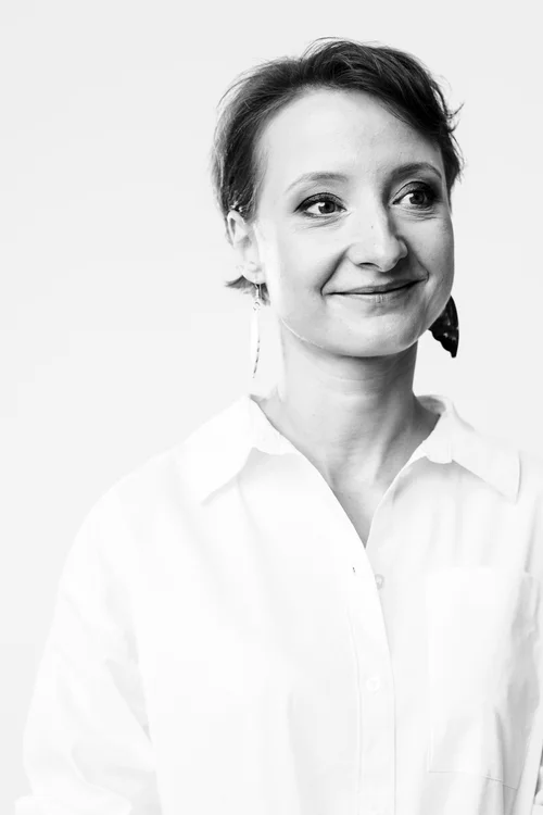 Czarno-białe zdjęcie młodej kobiety o upiętych z tyłu ciemnych włosach.