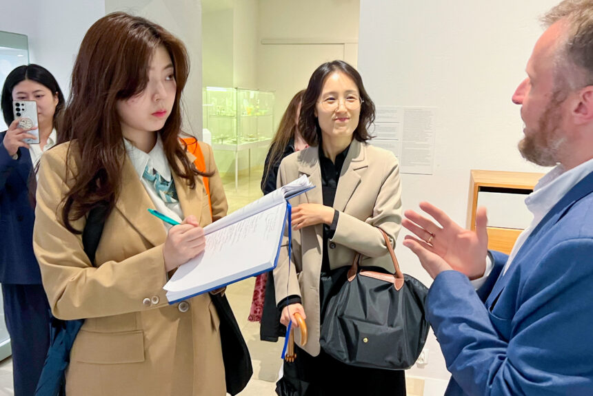 W sali Muzeum Sztuk Użytkowych trzy osoby koreańskiej delegacji słuchają prelekcji kierownika obiektu.