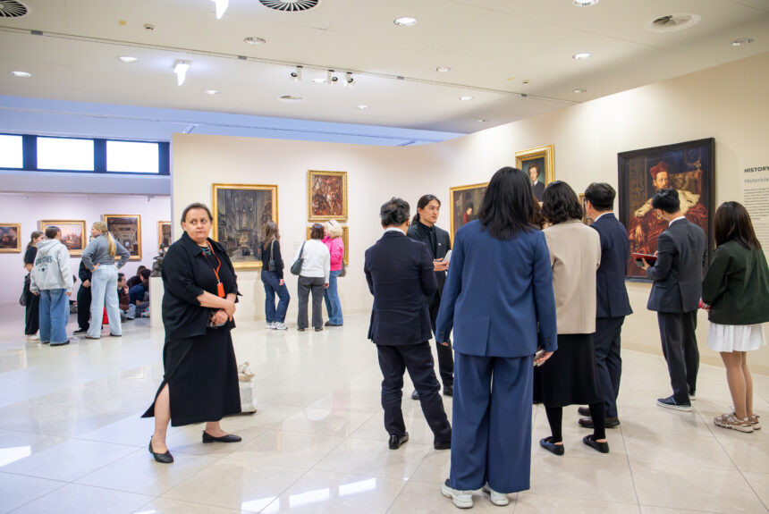 Wnętrze Galerii Malarstwa i Rzeźby. Koreańska delegacja zapoznaje się z dziełami sztuki wiszącymi na ścianach.