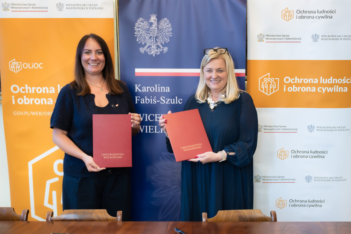 I Wicewojewoda Wielkopolska Karolina Fabiś-Szulc oraz Zastępca Dyrektora ds. Administracyjnych Agnieszka Purgat Dwie uśmiechnięte kobiety stoją obok siebie i pozują, trzymając teczki.